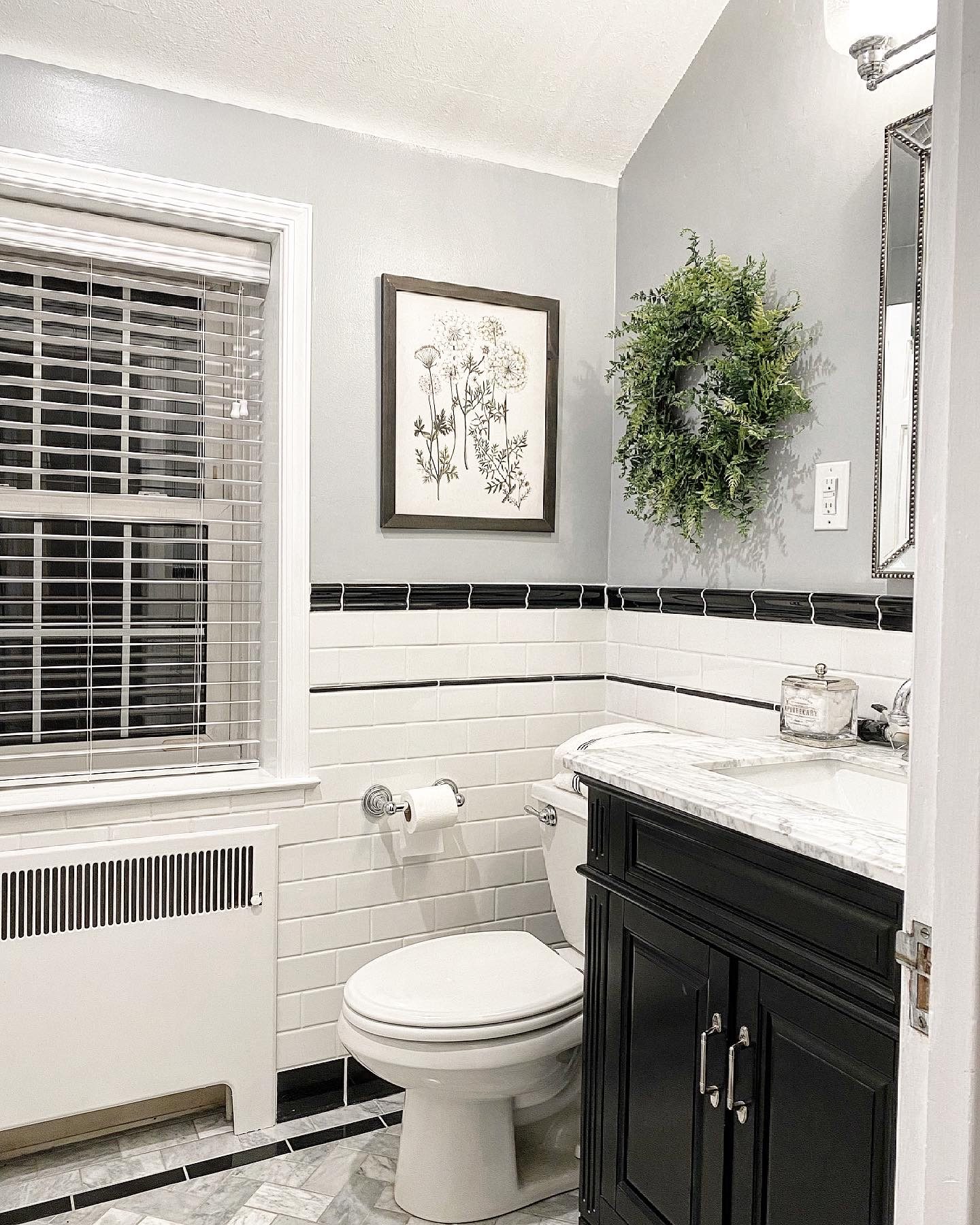 Renovated bathroom with white subway tile, black trim and a black vanity with marble top