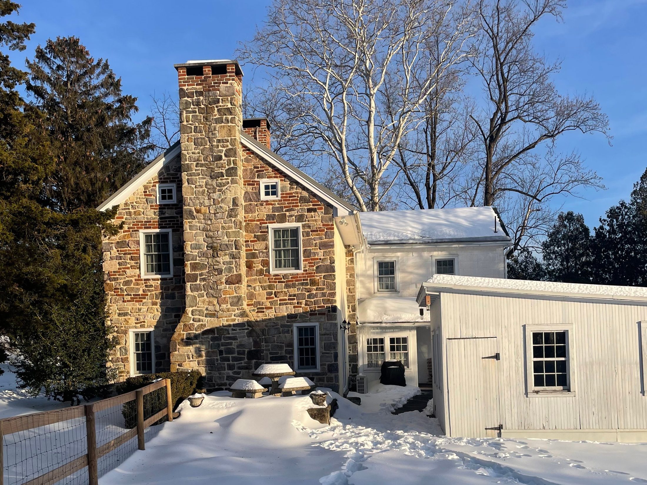 The same stone farmhouse before the addition, in snow, with an old white outbuilding at right