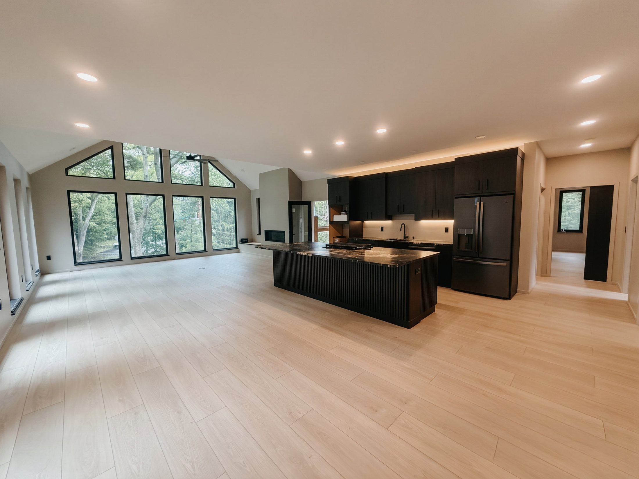 Open-plan living and kitchen with a wall of tall black-framed windows and a vaulted ceiling
