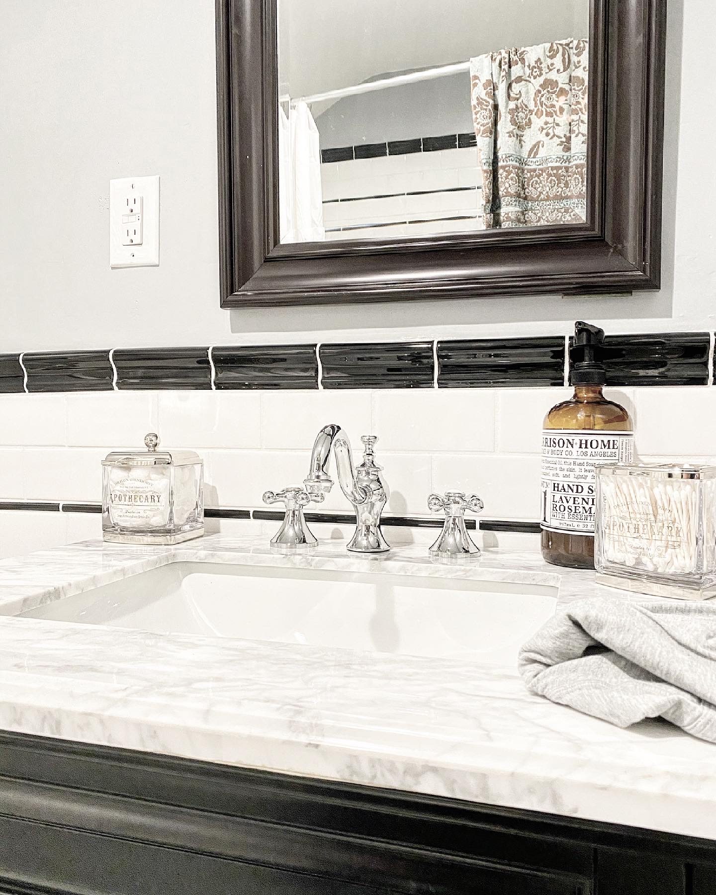 Vanity with marble top, polished chrome faucet and black tile border