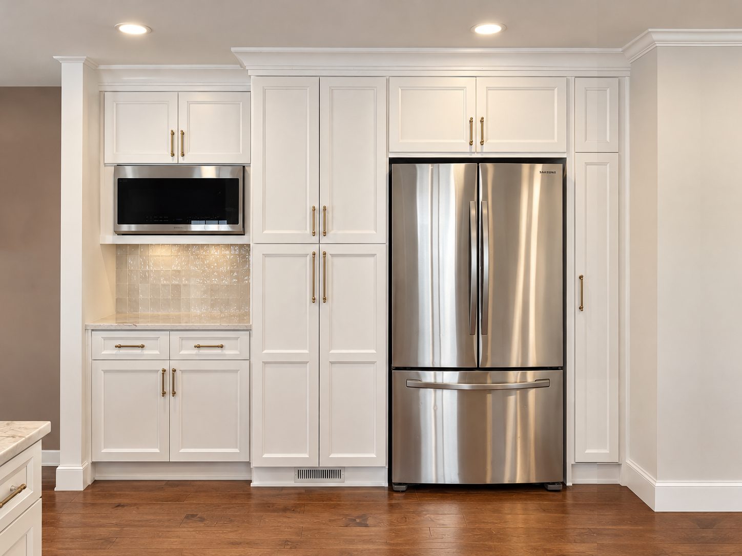 Built-in refrigerator wall with tall white pantry cabinets, microwave niche and handmade-look tile backsplash