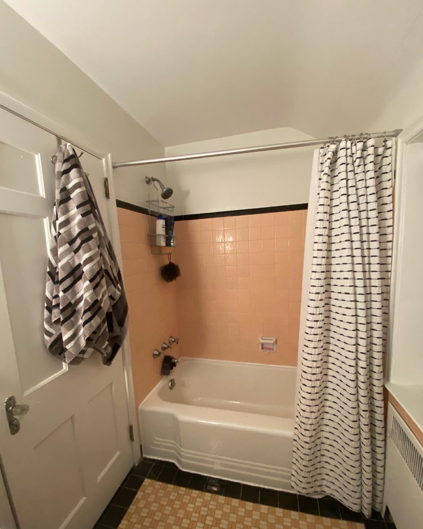 Before: bathtub with peach wall tile and black floor border