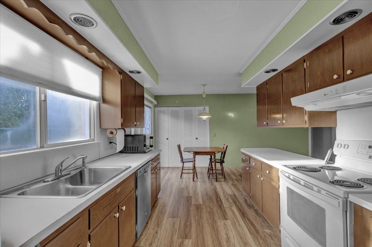 Before: galley kitchen with green walls, white laminate counters and an electric range