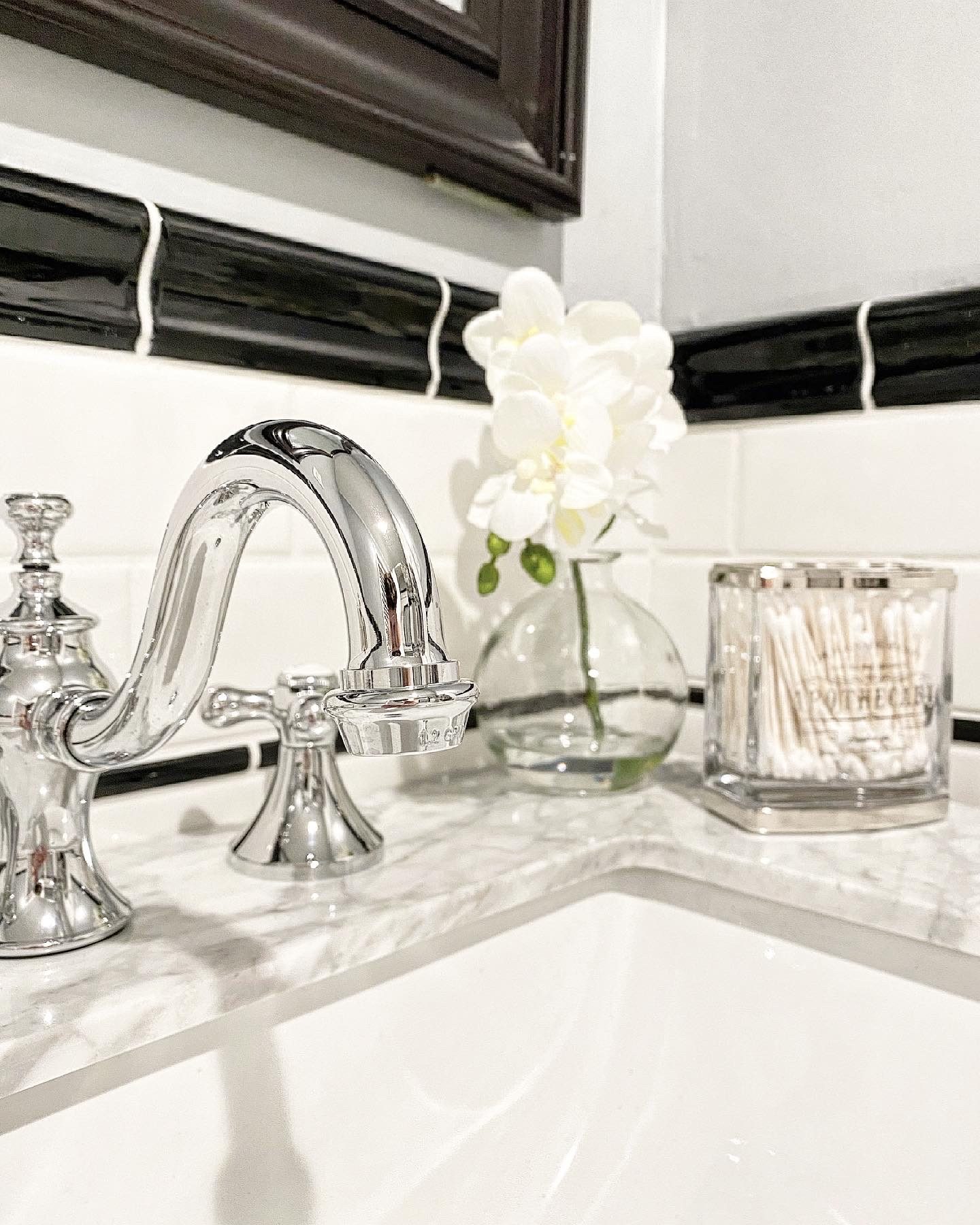Close view of the chrome faucet, glass vase and marble countertop