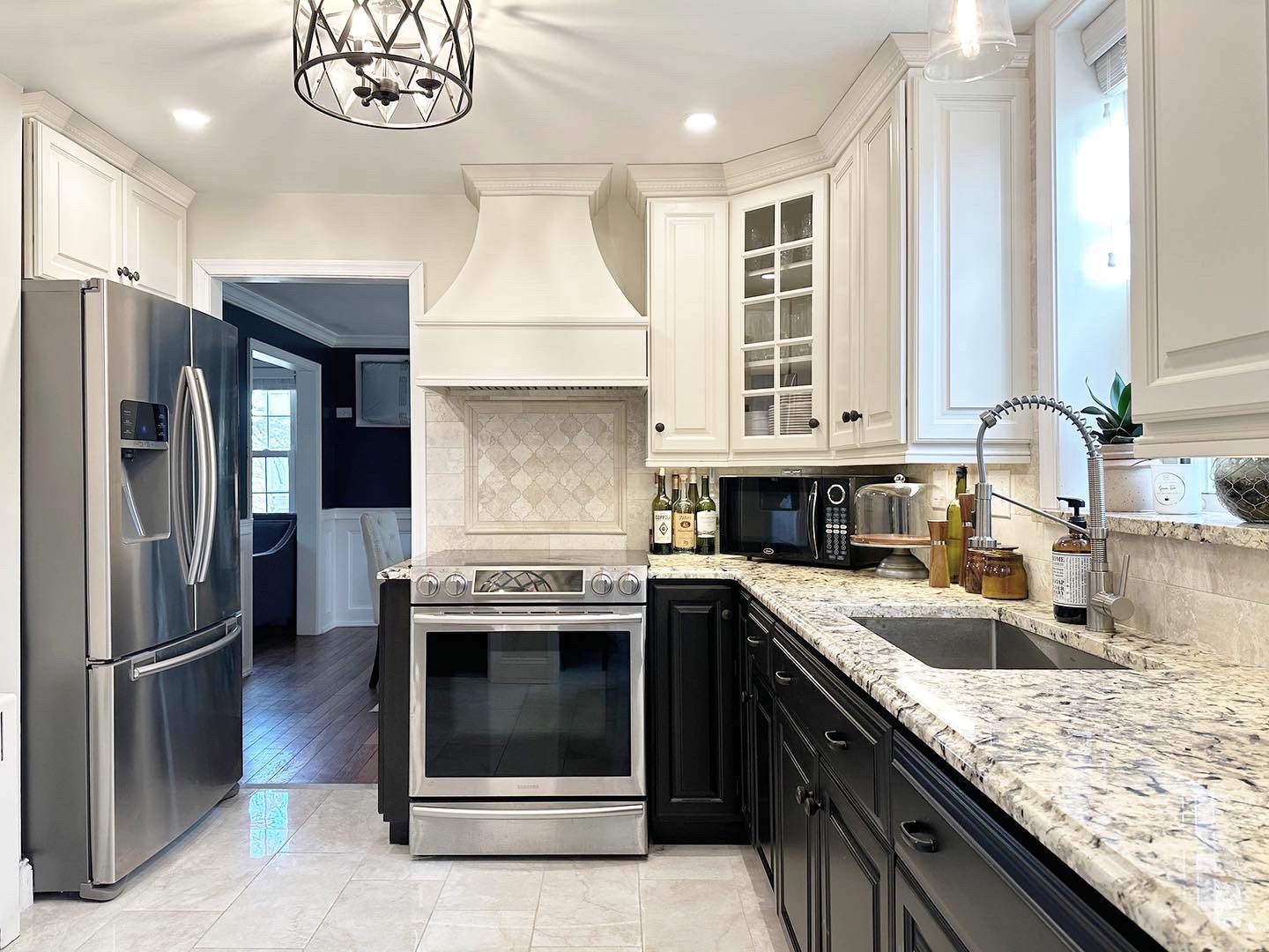 Renovated kitchen with white upper cabinets, black lower cabinets and granite counters
